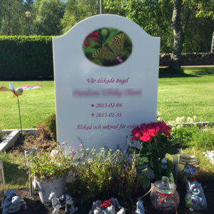 picture of installed peaceyard upright gravestone, model cora in glacier white material with customer graphics