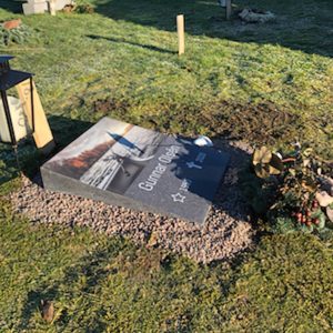 picture of installed peaceyard horizontal gravestone, model Flora in Midnight material with customer graphics